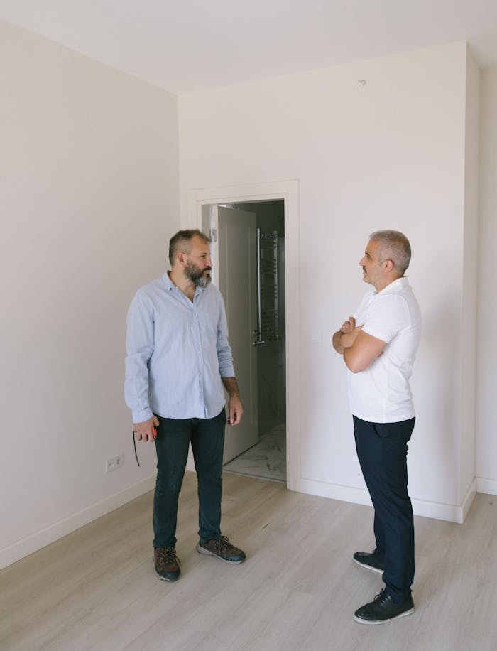 Two men stand discussing property in a modern Istanbul apartment with light interior.