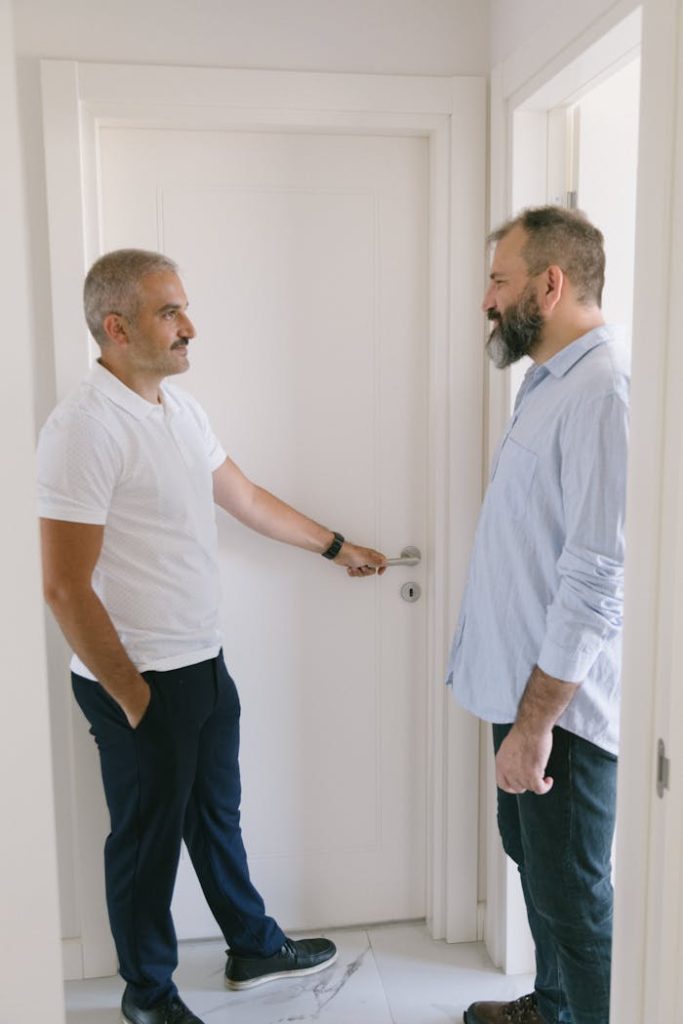 pexels photo 8978571 1 Two adult men conversing in an apartment hallway, emphasizing home lifestyle and interaction.