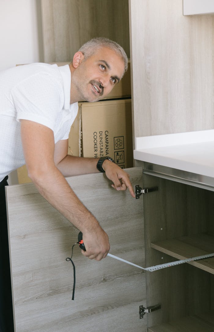 Crafting Captivating Headlines: Your awesome post title goes here Man in white shirt measuring kitchen cabinet with tape in Istanbul apartment. Ideal for real estate or DIY themes.